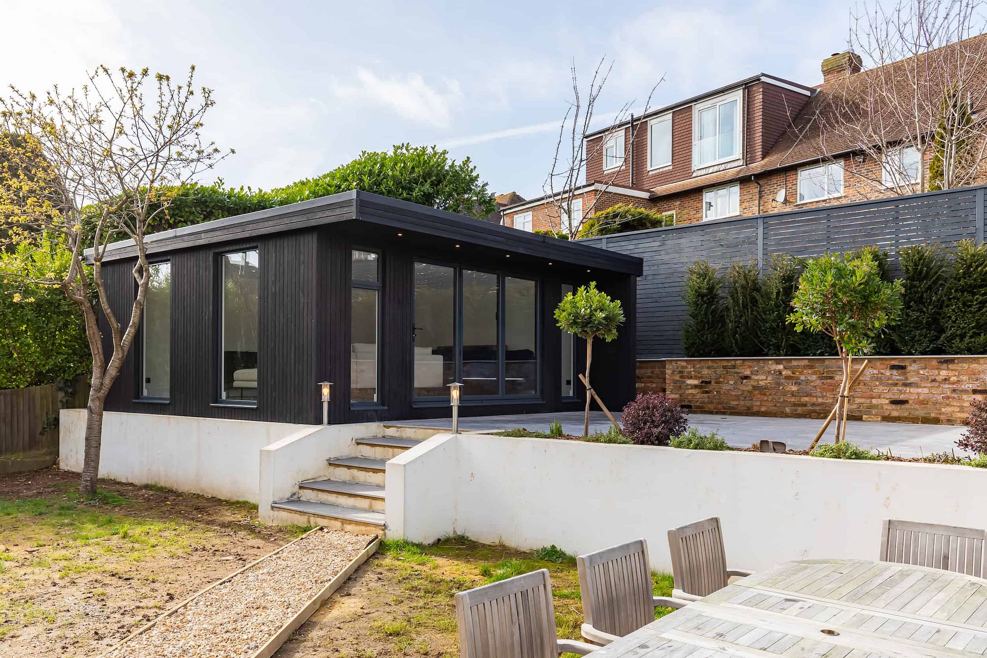 Garden room with landscaped garden and black wood exterior.